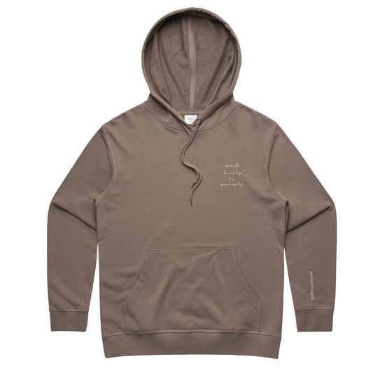 Speak Kindly to yourself written on a musk colored French Terry sweatshirt, with positive thoughts written down the side of the left handed sleeve.